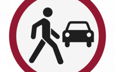 A man walkiing and an oncoming vehicle